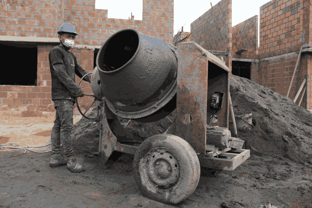 Construction worker with cement mixer at a black and white construction site